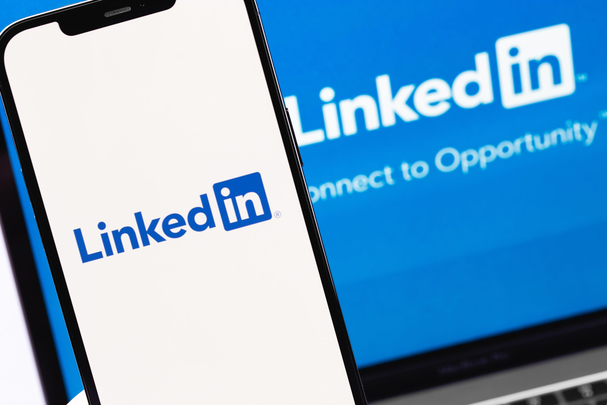 LinkedIn mobile app on screen smartphone iPhone and display notebook closeup. LinkedIn is a social network for finding and establishing business contacts. Moscow, Russia - January 17, 2022