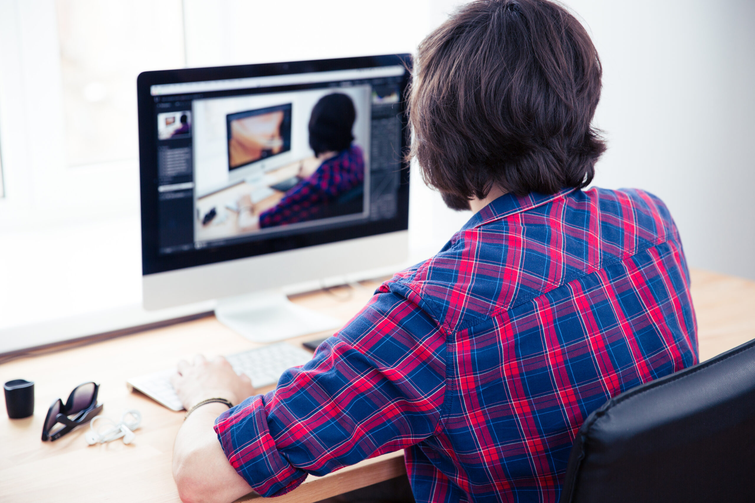 Back view portrait of a male photo editor working on computer in office